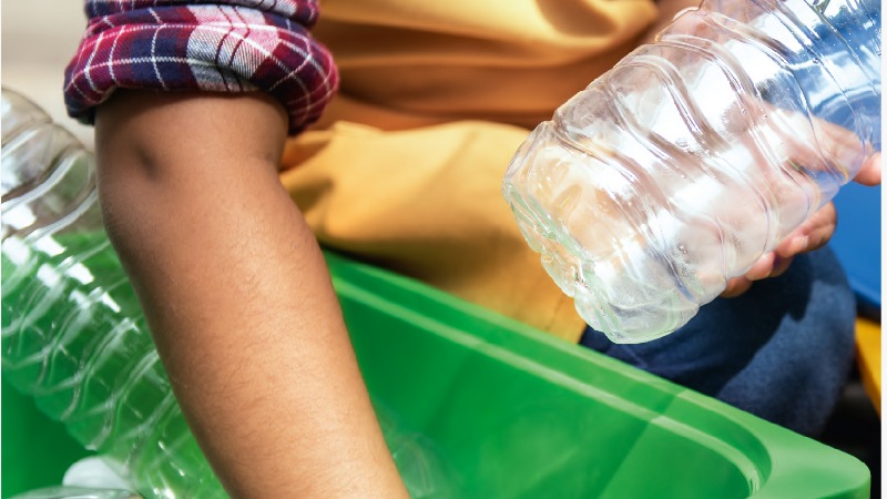 La información sobre la Guía de buenas prácticas ambientales está acompañada por una imagen parcial de un niño, manipulando botellas de plástico transparentes en una batea cuadrada de color verde